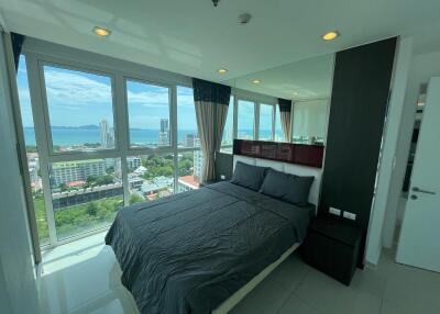 Modern bedroom with large windows showcasing a city and sea view