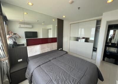 Modern bedroom with a large bed, mirrored wall, flat screen TV, built-in wardrobe, and air conditioning