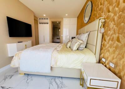 Modern and stylish bedroom with bed, TV, wall clock, bedside table, and attached bathroom