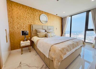 Luxurious bedroom with large window, gold accent wall, and modern decor