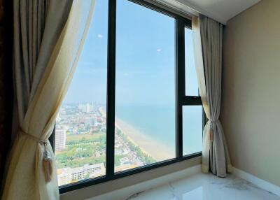 Bedroom with large windows offering a panoramic view of the city and ocean