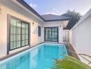 Outdoor pool area of modern house with large windows and sliding doors