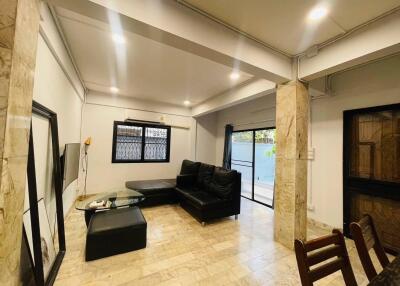 Contemporary living room with marble flooring, black sofa, and ample lighting.