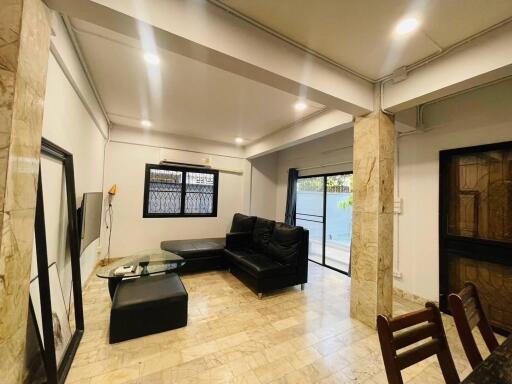 Contemporary living room with marble flooring, black sofa, and ample lighting.