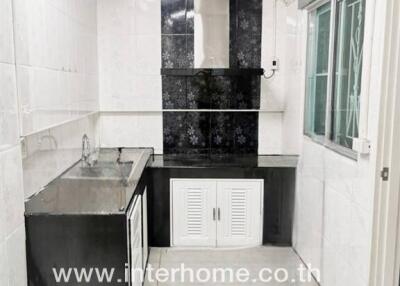 modern kitchen with stainless steel sink and black backsplash