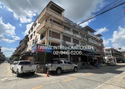 Street view of a multi-story residential building with businesses on the ground floor