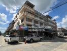 Street view of a multi-story residential building with businesses on the ground floor