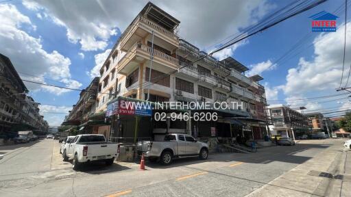 Street view of a multi-story residential building with businesses on the ground floor