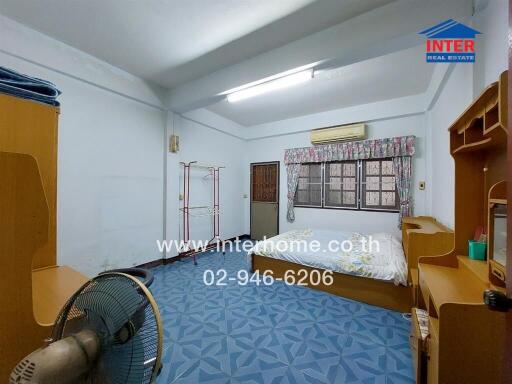 Bedroom with blue patterned floor, bed, and wooden furniture