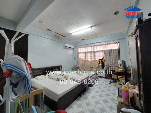 Bedroom with bed, large window, and various belongings