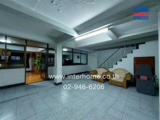 Spacious living room with tile flooring, two sofas, and a staircase