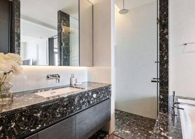 Modern bathroom with marble countertop, fitted mirror, and walk-in shower