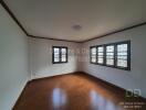 Spacious empty bedroom with wooden floor and large windows