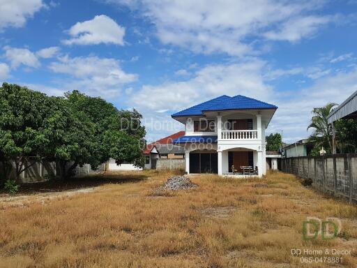 Two-story house with blue roof and large yard