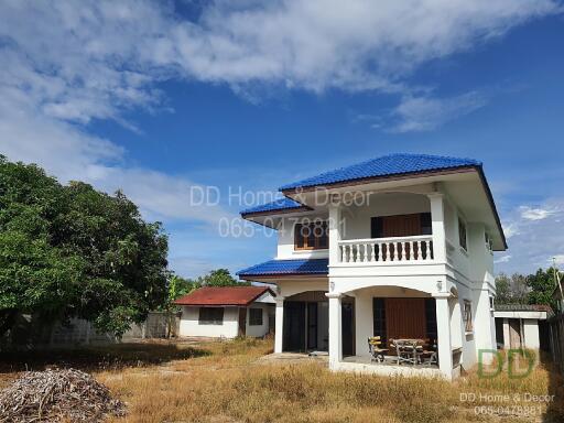 Two-story house with blue roof and surrounding yard