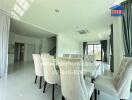 Modern dining room with white chairs and table, large windows, and staircase