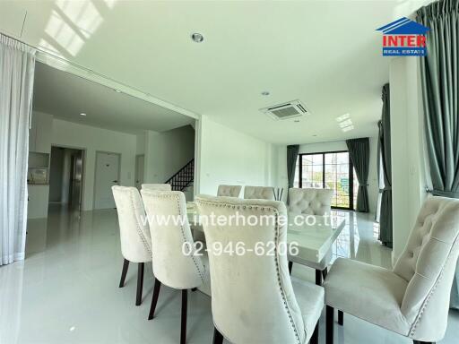 Modern dining room with white chairs and table, large windows, and staircase