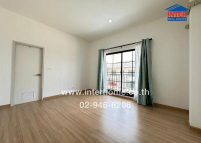 Spacious living room with wooden floors and large window with curtains