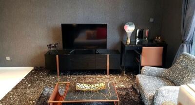 Modern living room with TV, coffee table, armchair, and workspace