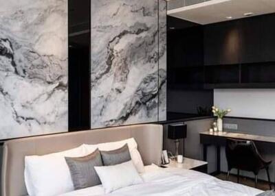 Modern bedroom with a bed, decorative marble wall, desk, and chair.