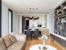 Modern living room with a view of dining area and kitchen, featuring stylish hanging lights and wooden flooring.