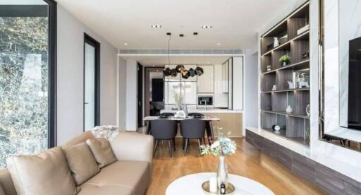 Modern living room with a view of dining area and kitchen, featuring stylish hanging lights and wooden flooring.