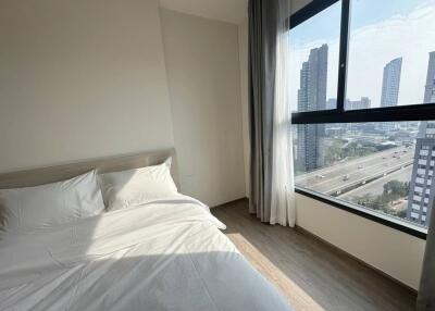 Bedroom with a large window and urban view
