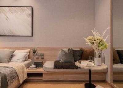 Modern bedroom with a cozy bed, decorative cushions, a side table with a vase of flowers, and a large wall mirror