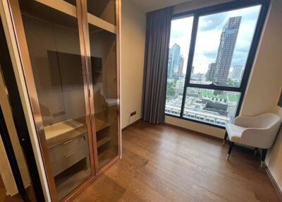 Bedroom with wooden flooring, large window with city view, built-in closet, and armchair