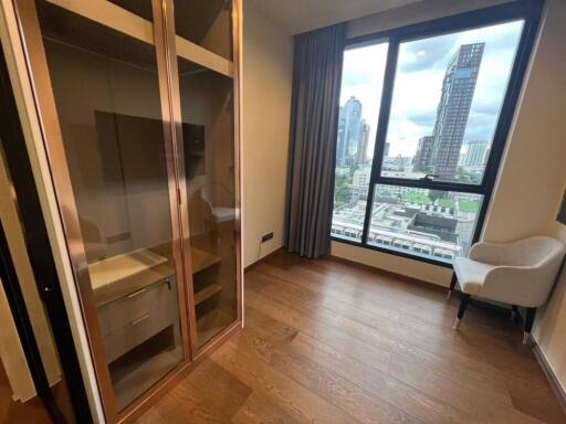 Bedroom with wooden flooring, large window with city view, built-in closet, and armchair