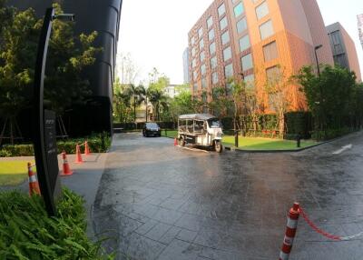 entrance driveway of a residential building with greenery and a parked vehicle