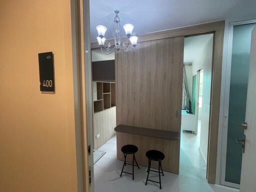 Modern living area with chandelier, bar stools, and sliding wooden partition