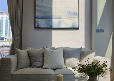 Bright living room with a gray sofa, decorative pillows, and a modern painting on the wall