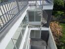 Exterior view of a modern multi-level building with rooftop terrace and spiral staircase