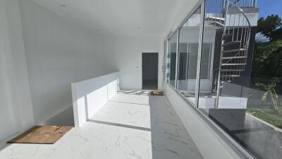 Modern hallway with marble floor and large windows, featuring a spiral staircase leading to an upper level.