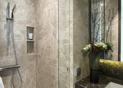 Modern bathroom with walk-in glass shower and marble walls