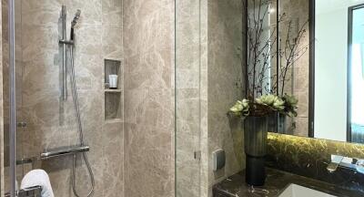 Modern bathroom with walk-in glass shower and marble walls