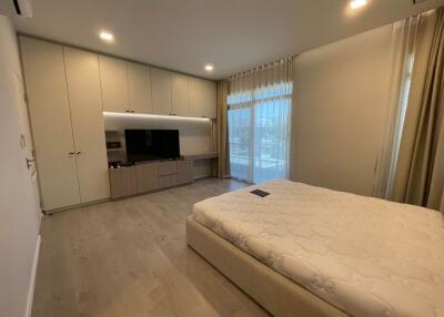Spacious bedroom with built-in wardrobe, large windows, and a mounted TV