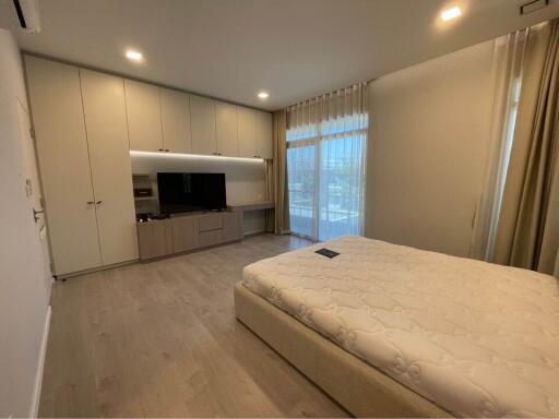 Spacious bedroom with built-in wardrobe, large windows, and a mounted TV