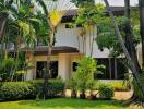 A two-story house with lush greenery surrounding it