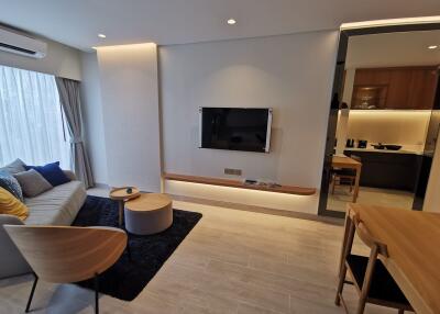 Modern living room with wall-mounted TV and kitchen view
