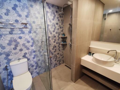 Modern bathroom with glass shower, toilet, and vanity