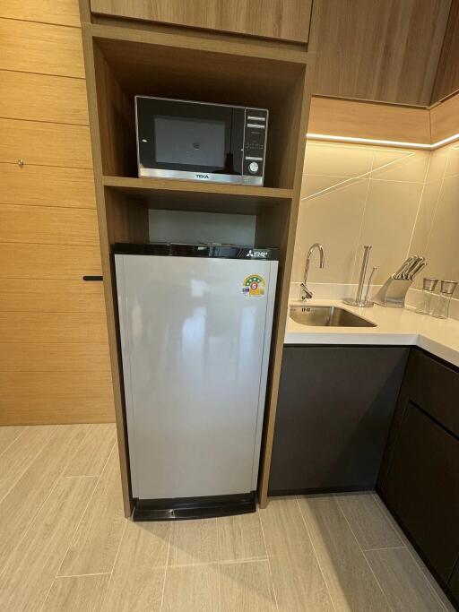 Compact kitchen with refrigerator, microwave, sink, and cabinets