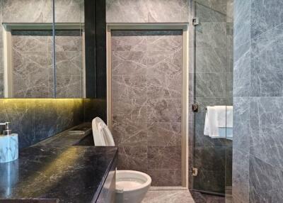 Modern bathroom with marble tiles, glass shower door, and sink with mirror