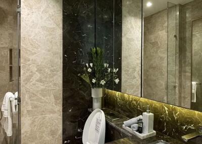 Modern bathroom with beige marble walls, shower area, and a dark marble countertop