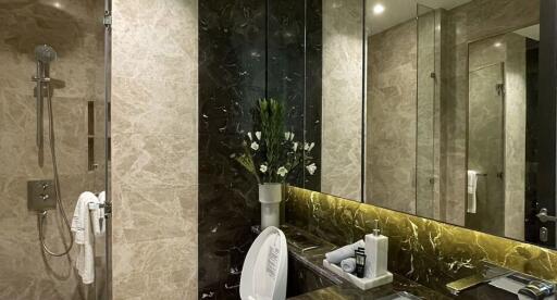 Modern bathroom with beige marble walls, shower area, and a dark marble countertop