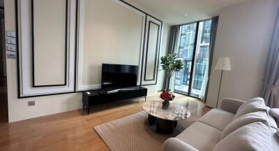 Modern living room with TV, sofa, coffee table, and large window