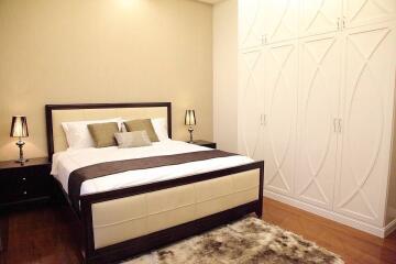 Modern bedroom with double bed, lamps on bedside tables, large wardrobe, and carpet