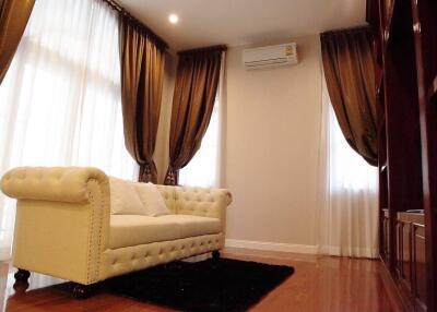 Spacious and elegant living room with large windows, draped curtains, and a comfortable couch