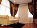 Spacious and elegant living room with large windows, draped curtains, and a comfortable couch